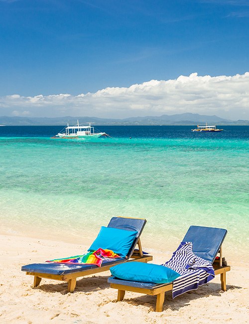Île basse bordée de cocotiers et lagon turquoise — archipel de Balabac, sud de Palawan